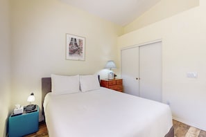 A bedroom with a bed, a nightstand, a dresser, a lamp, a picture on the wall, and a door. - Modern home with large yard, mountain views, & convenient location (Phoenix)