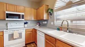 A kitchen with wooden cabinets, a microwave, stove, dishwasher, and a sink. - Modern home with large yard, mountain views, & convenient location (Phoenix)