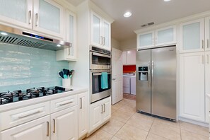 A modern kitchen with white cabinets, stainless steel appliances, and a tiled backsplash. - Dog-friendly desert retreat with lovely pool & spa - minutes to Tennis Garden (Palm Desert)