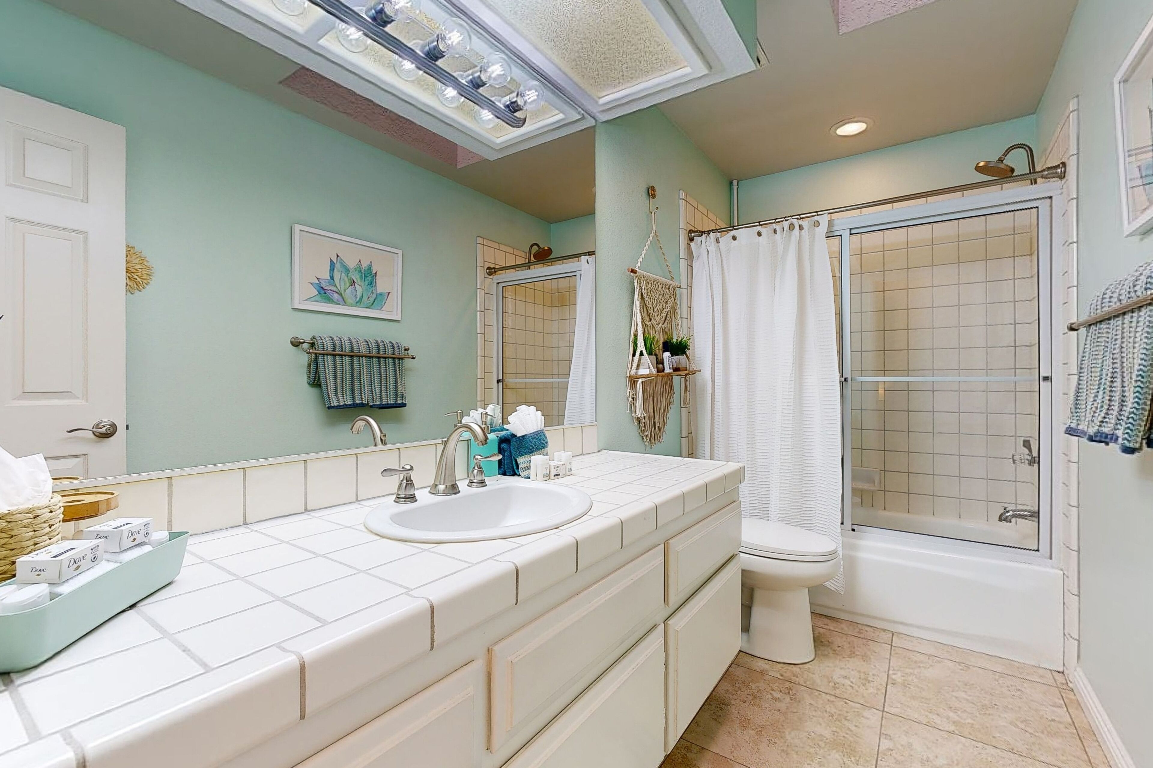 A bathroom with a large vanity, two sinks, a toilet, and a shower area.