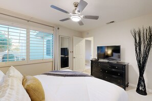 A bedroom with a bed, a ceiling fan, a dresser, a television, and a large window with blinds. - Dog-friendly desert retreat with lovely pool & spa - minutes to Tennis Garden (Palm Desert)