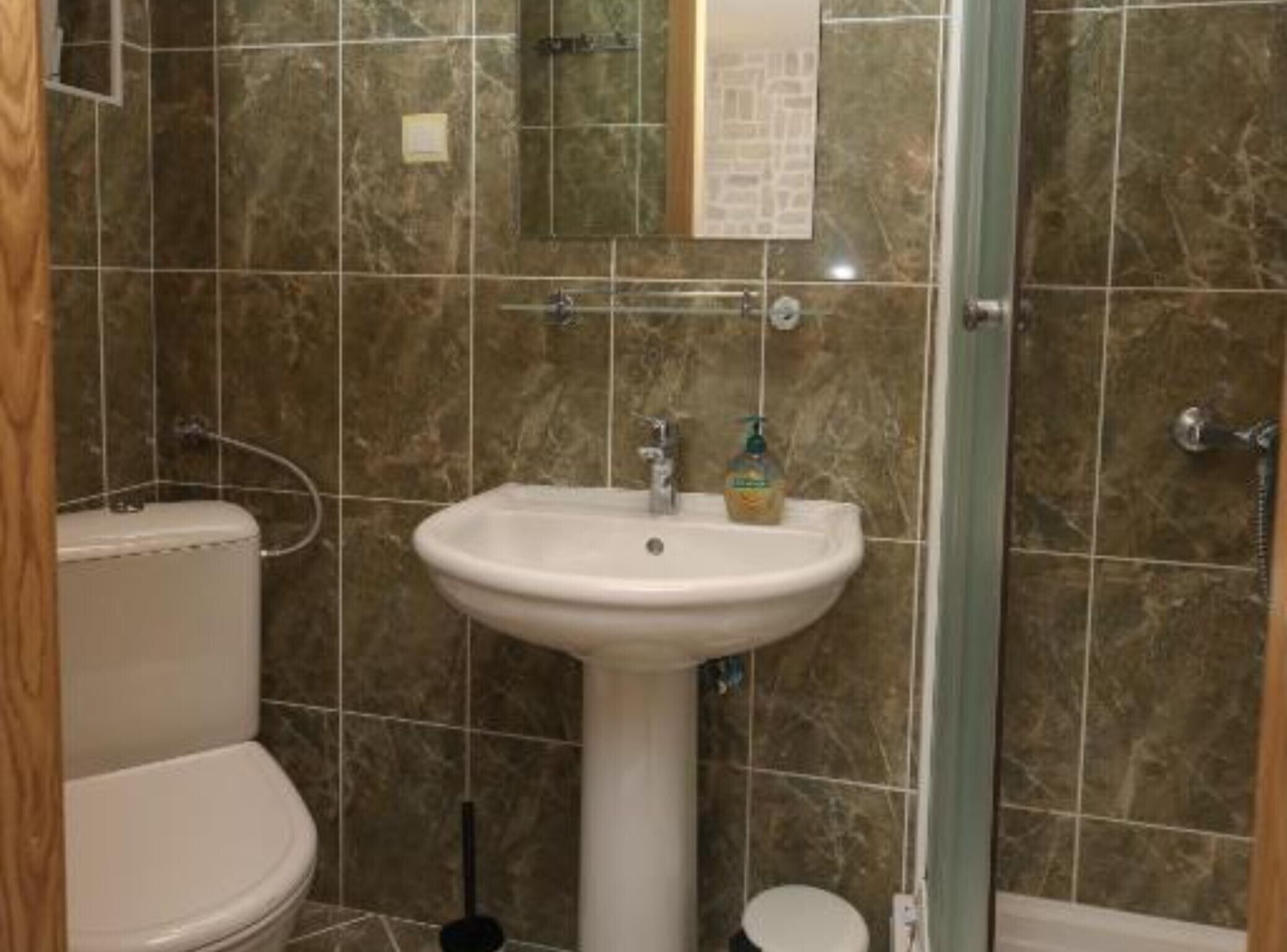A bathroom with a toilet, sink, and mirror.