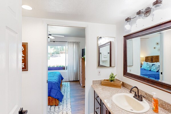 A modern bathroom with a large mirror, a sink, and a shower area. - Golf-course-front home with private pool, spa, terrace & mountain view (Oro Valley)