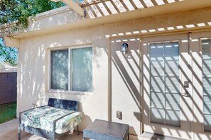 A small, single-room house with a bed, a table, and a window. - Spacious townhome with movie room, patios, pool, & home office (Scottsdale)
