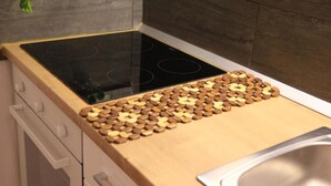 Une cuisine dotée d’une plaque de cuisson à induction noire, d’une planche à découper en bois et d’un évier en acier inoxydable.