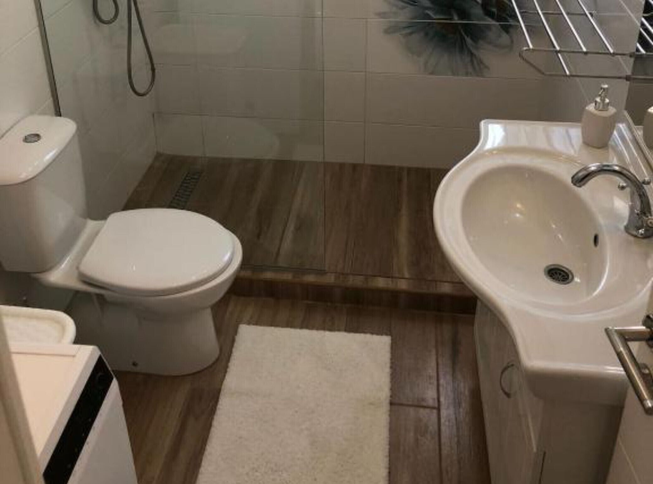 Un bagno con il water, un lavandino e pavimento in legno.