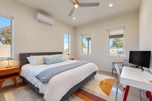 A bedroom with a bed, bedside tables, a desk, a chair, a television, and a ceiling fan. - Charming Chandler retreat with pool, guest house, pickleball and putting green! (Chandler)