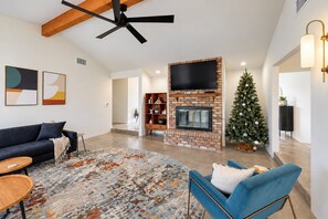 A modern living room with a fireplace, a ceiling fan, and a Christmas tree. - Charming Chandler retreat with pool, guest house, pickleball and putting green! (Chandler)
