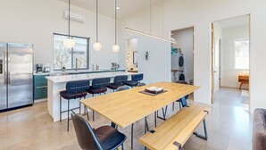 Eine moderne Küche mit einer zentralen Kochinsel, Barhocker und einem Holztisch mit Bänken.