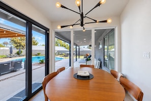 A modern dining area with a wooden table, chairs, and a pendant light fixture.