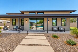A modern house with a pool, outdoor seating, and a clear view of the backyard. - Charming Chandler retreat with pool, guest house, pickleball and putting green! (Chandler)