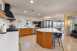 A modern kitchen with a central island, stainless steel appliances, and a large window providing natural light. - Charming Chandler retreat with pool, guest house, pickleball and putting green! (Chandler)