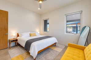A bedroom with a bed, bedside tables, a window, a mirror, and a view of the outside.