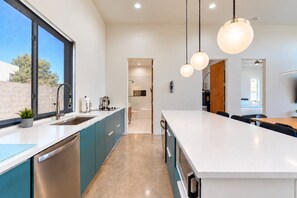 A modern kitchen with a large island, built-in appliances, and pendant lighting.