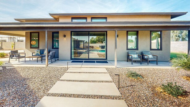 Ein modernes Haus mit Terrasse, Sitzgelegenheit im Freien und einem Swimmingpool.