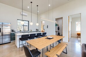 A modern kitchen with a central island, stainless steel appliances, pendant lighting, and a view to the outside. - Charming Chandler retreat with pool, guest house, pickleball and putting green! (Chandler)
