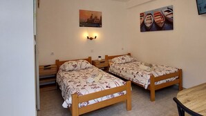 Una habitación con dos camas de madera, una mesita y una lámpara fijada a la pared.