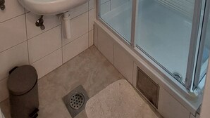 Baño con lavamanos, inodoro, ducha y desagüe en el suelo.