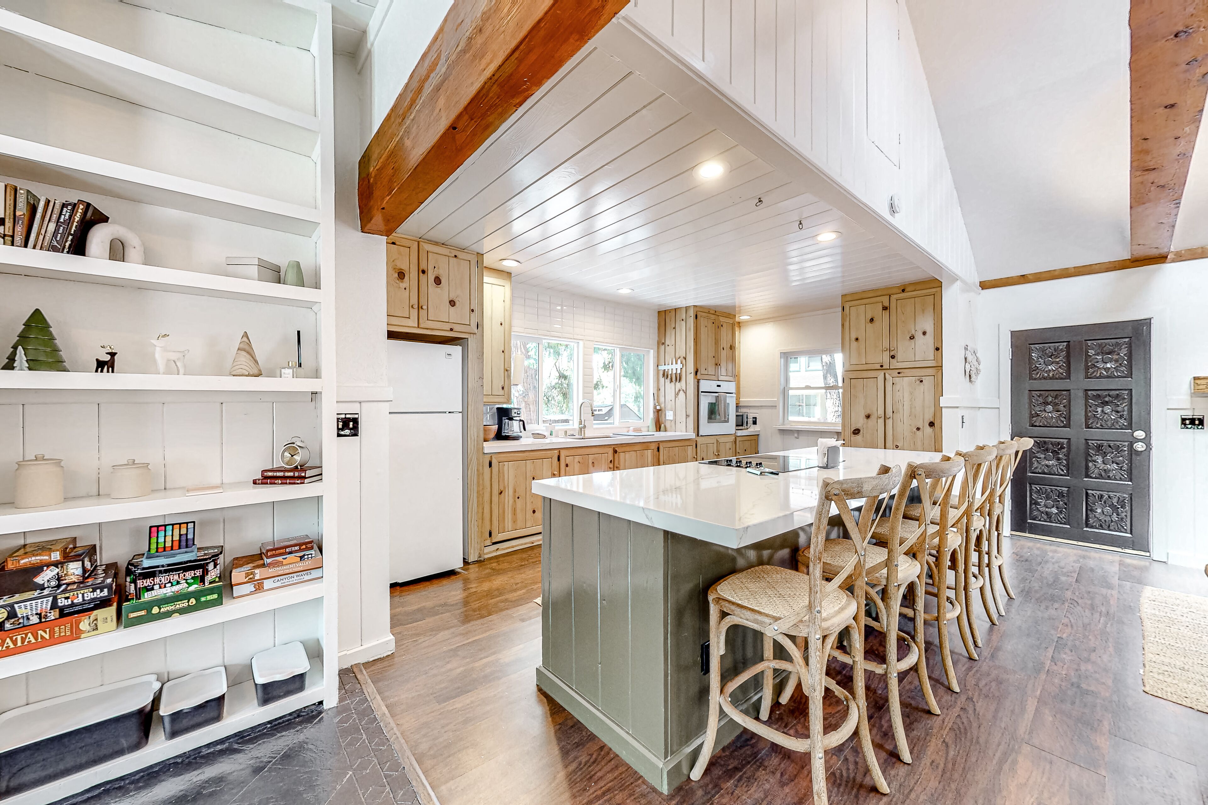 Una cocina amplia con armarios de madera, una isla central y un comedor con taburetes de bar.