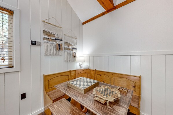 A room with a wooden headboard bed, a checkered table, and a wall-mounted macrame piece.