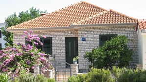 A two-story building with a tiled roof, brick walls, and a small garden with flowering plants. - Casa Dolce Mare - ThreeBedroom Holiday Home with Terrace (Pasman)