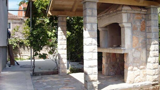 A stone-built outdoor oven structure with a tiled roof, surrounded by a stone-paved area and greenery. - Casa Dolce Mare - ThreeBedroom Holiday Home with Terrace (Pasman)