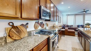 A modern kitchen with granite countertops, wooden cabinets, a built-in oven, and a microwave. - Modern 55+ home with community pool, clubhouse, gym, pickleball (Goodyear)