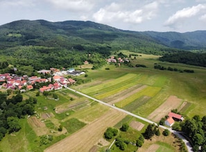 An aerial view of a rural village with houses, fields, and mountains in the background.