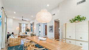 A spacious dining area with a long wooden table, wicker chairs, and a hanging light fixture. - Designer dream home with opulent backyard, private pool, hot tub, game room & AC (Scottsdale)