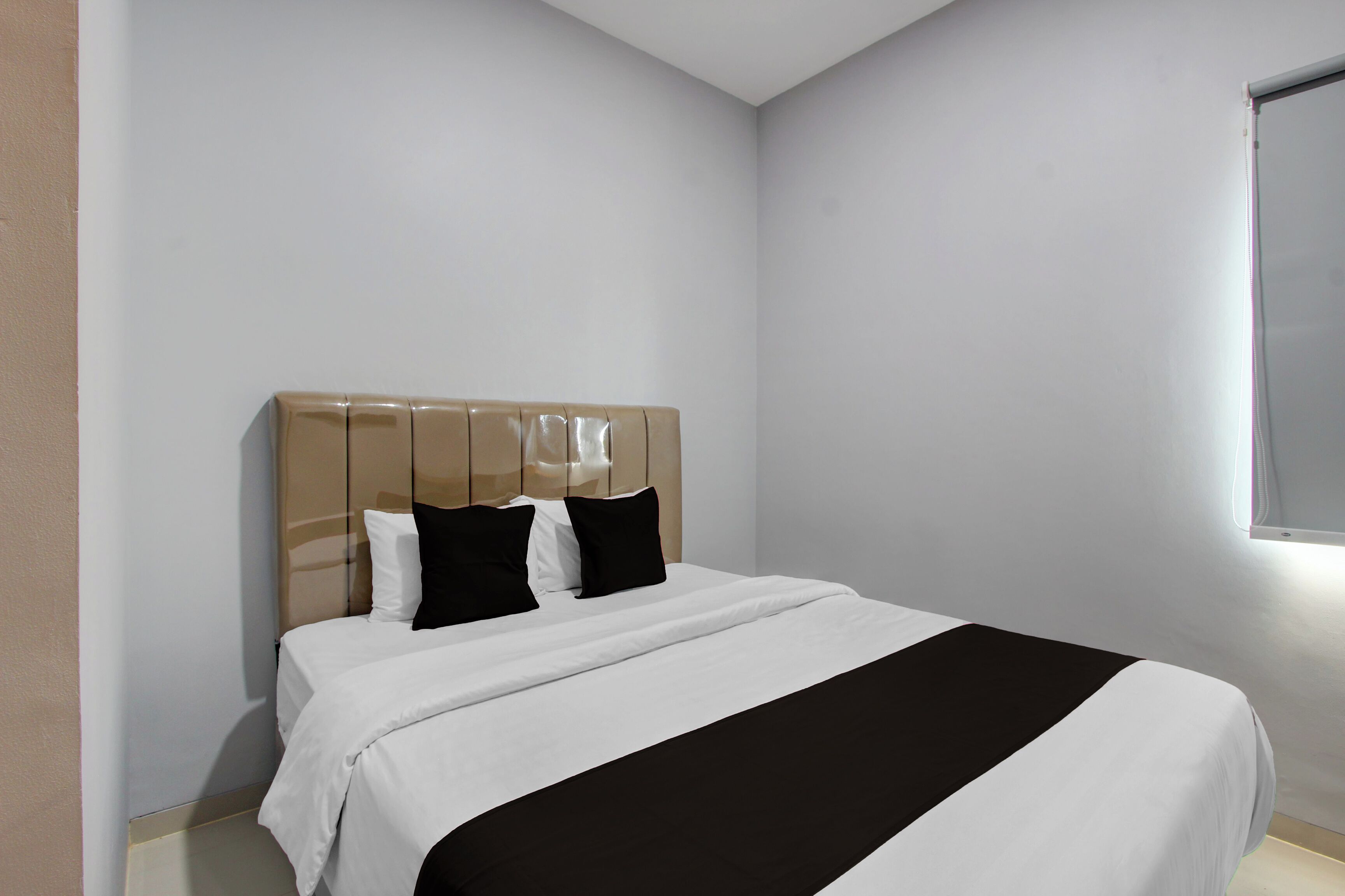 Un dormitorio con cama, cabecera y ventana.