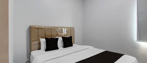 Un dormitorio con cama, cabecera y ventana.
