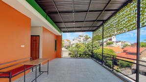 Un balcon doté d’un sol à motifs, d’un banc et offrant une vue sur des immeubles et des arbres.