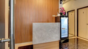 Un espace d’accueil doté d’un comptoir en marbre, d’un mur recouvert de panneaux en bois et d’un réfrigérateur décoré de fleurs.