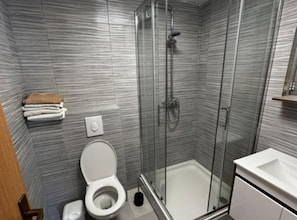 A bathroom with a shower, toilet, and sink.