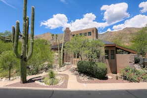 A desert-style building with a stone facade, surrounded by cacti and desert plants.