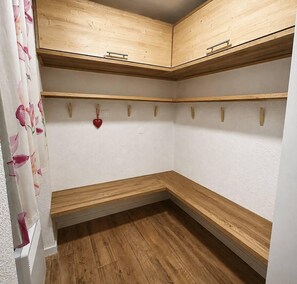 A corner closet with wooden shelves and a bench, a red heart decoration, and a floral curtain. - 130m from ski slopes, 9th floor, view ski slopes, balcony, ski locker, 73m², Méribel-Mottaret (Méribel - Les Allues)