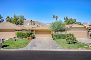 A residential area with houses, a driveway, and a mountain in the background. - Bright and cheery home close to Coachella with pool & tennis on-site (Palm Desert)
