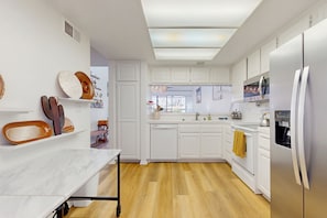 Een moderne keuken met witte kasten, een marmeren aanrecht en een houten vloer.