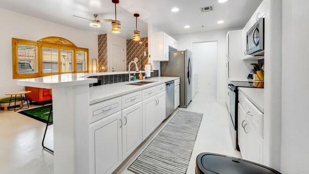 A modern kitchen with white cabinetry, a central island, stainless steel appliances, and pendant lighting. - Vibrant, dog-friendly escape on bike path with washer/dryer, AC, pool, & hot tub (Tucson)
