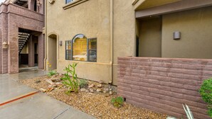 A building with a brick facade, a small window with shutters, and a gravel area with plants. - Vibrant, dog-friendly escape on bike path with washer/dryer, AC, pool, & hot tub (Tucson)