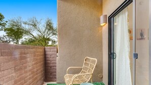 A wicker chair, a small stool, and a glass door with a curtain. - Vibrant, dog-friendly escape on bike path with washer/dryer, AC, pool, & hot tub (Tucson)