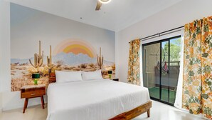 A bedroom with a large bed, a mural of a desert landscape, a sliding glass door, and a green nightstand. - Vibrant, dog-friendly escape on bike path with washer/dryer, AC, pool, & hot tub (Tucson)