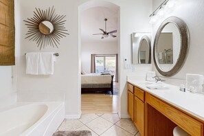 A modern bathroom with a bathtub, a vanity with a mirror, and a ceiling fan. - Scottsdale Oasis – Poolside Paradise Near Golf, Shopping & Freeways! (Scottsdale)
