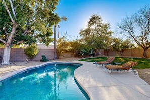 A backyard with a swimming pool, two lounge chairs, and a small garden area. - Scottsdale Oasis – Poolside Paradise Near Golf, Shopping & Freeways! (Scottsdale)