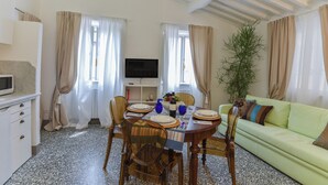 Un coin repas avec une table dressée pour quatre personnes, un téléviseur et un canapé vert.