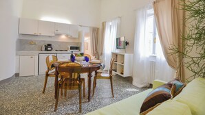 Une cuisine compacte avec des meubles blancs, une table à manger avec des chaises, un four à micro-ondes et une machine à café.