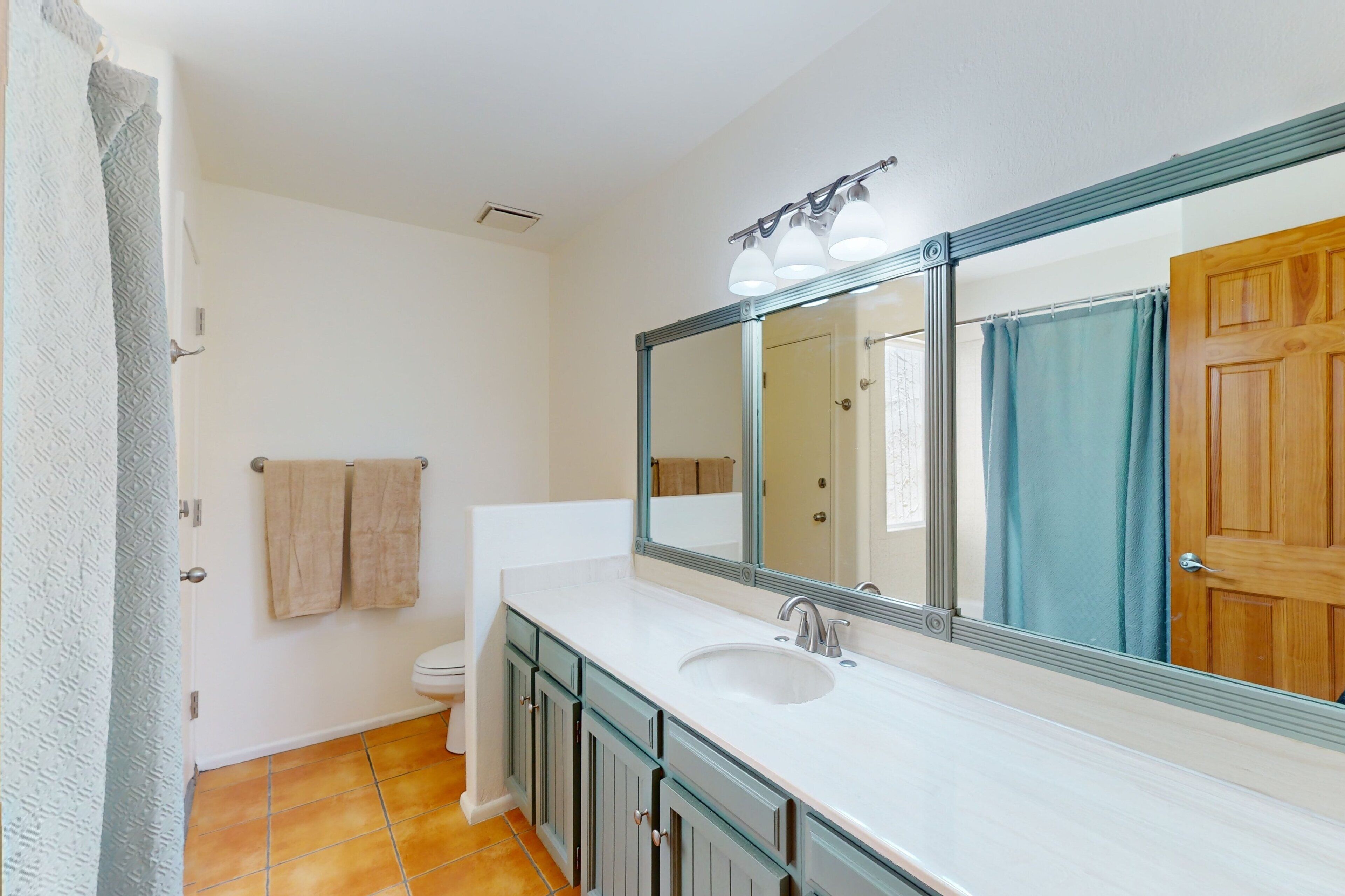 A bathroom with a white sink, a large mirror, and a wooden door.