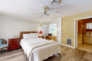 Une chambre à coucher comprenant un lit, une commode, une table de chevet et un ventilateur de plafond.