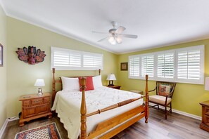 A bedroom with a four-poster bed, two bedside tables, a chair, and a ceiling fan. - Eclectic mid-century, dog-friendly home with private pool, yard & gas grill (Palm Springs)