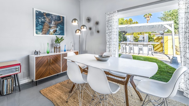 Een moderne eethoek met een witte tafel, witte stoelen en een houten kast.
